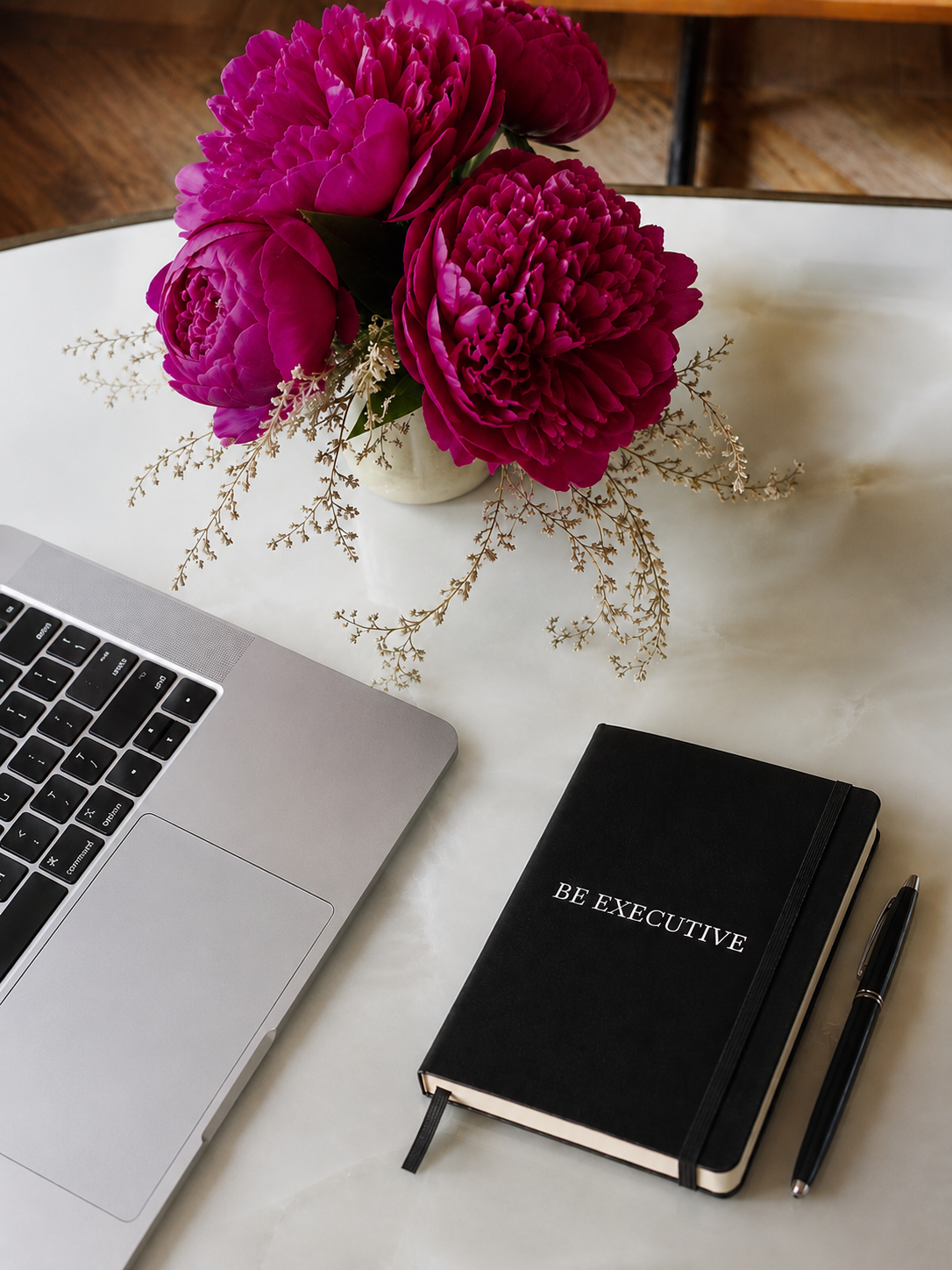 Taccuino Be Executive su una scrivania con laptop e peonie